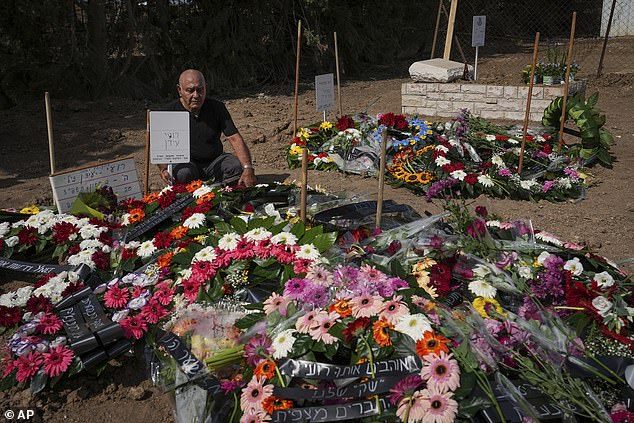 Following the deaths of Israeli news photographer Roy Edan and his wife Smadar, Edan's father sits next to the couples' graves during their funeral in Kfar Harif, Israel, on October 20.