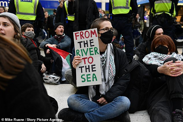 Protesters in London take part in a sit-in at Victoria Station, holding signs calling for the eradication of Israel