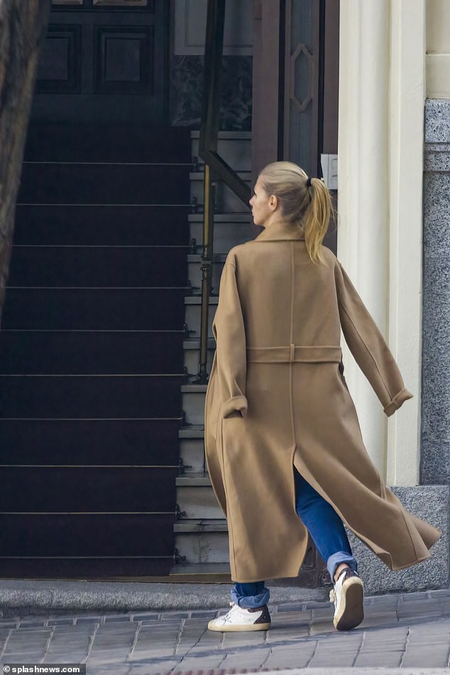 Genoveva, wearing jeans and a brown jacket, is seen entering an apartment building