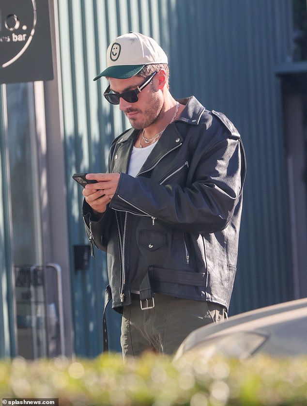 Casual: The star wore a baseball cap, white T-shirt and leather jacket, paired with khaki green pants as he walked