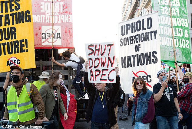 Protesters hold signs during the action "No on APEC" protesting on the sidelines of the conference