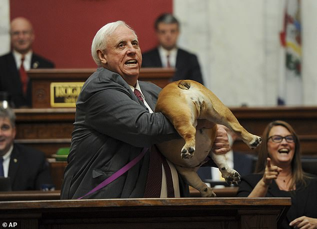 West Virginia Governor Jim Justice holds up the back of his dog Babydog as a message to haters during his State of the State address in the House chambers