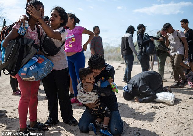 A migrant family from Venezuela reacts after breaking through a barbed wire barricade into the United States