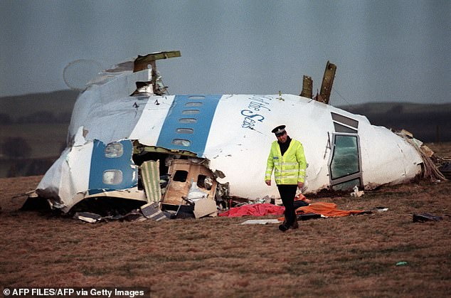 A file photo taken on December 22, 1988 shows a police officer walking away from the damaged cockpit of the Pan Am plane that exploded and crashed with 259 passengers on board