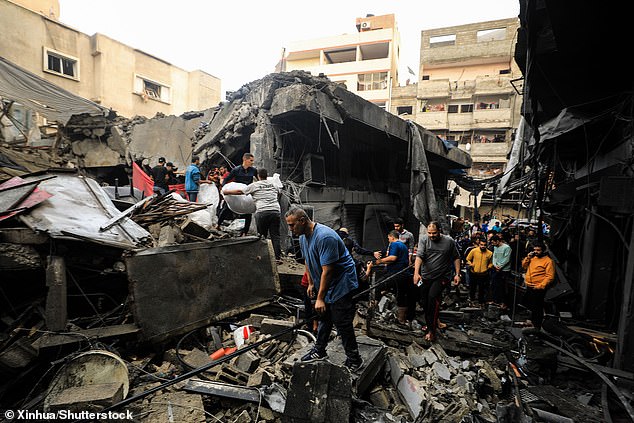 People collect items from the rubble of buildings destroyed during Israeli airstrikes in the town of Khan Younis in the southern Gaza Strip