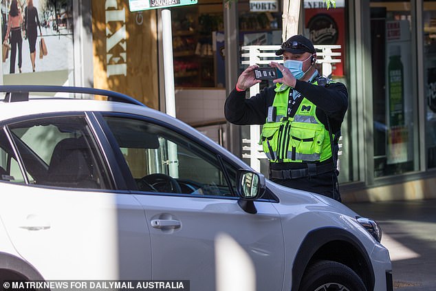 A parking inspector is pictured issuing a parking ticket in Melbourne, although different rules apply to them