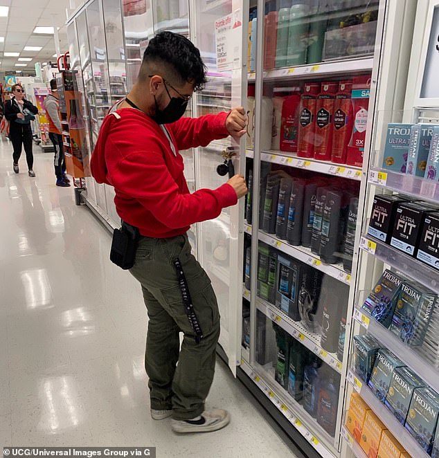 A Target employee closes one of the cabinets containing men's deodorant.  The company predicted a loss of $500 million per year to violent shoplifters