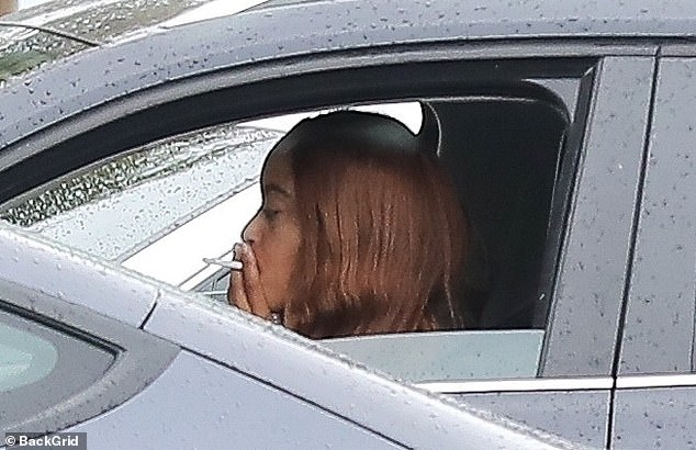 After lunch, she smoked a cigarette in her car with the driver's side window open on a rainy day