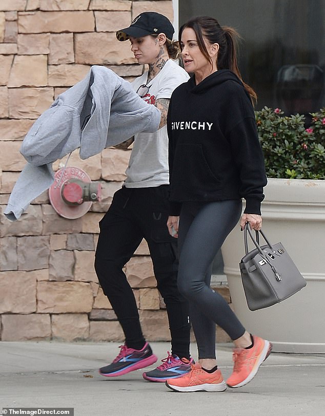 Stylish duo: Adding gray leggings, bright orange sneakers and a designer bag to the mix, Kyle kept a low-key vibe with purple-tinted sunglasses