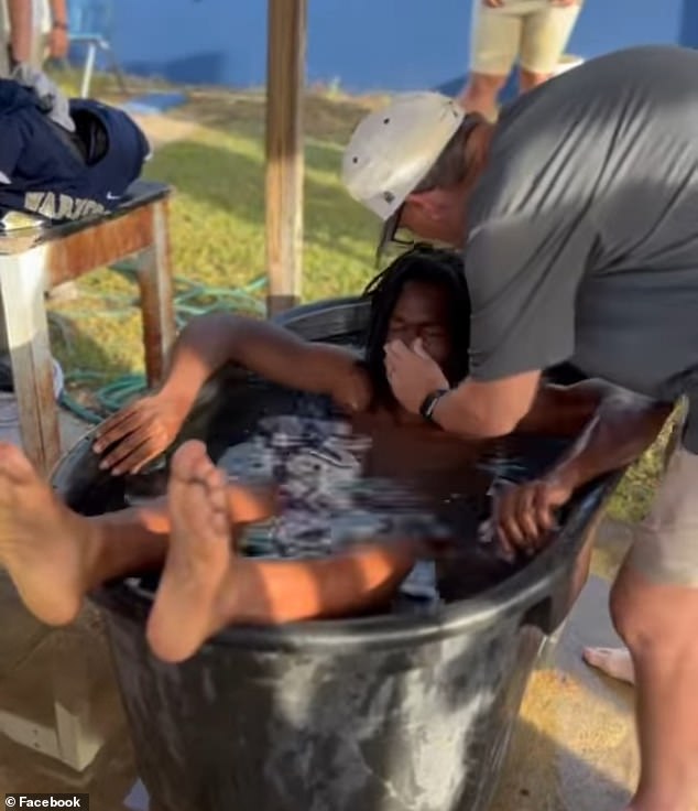 A total of twenty players lined up to get into the big black bucket of water and have their heads immersed by a local pastor.  Video of the baptisms was posted online