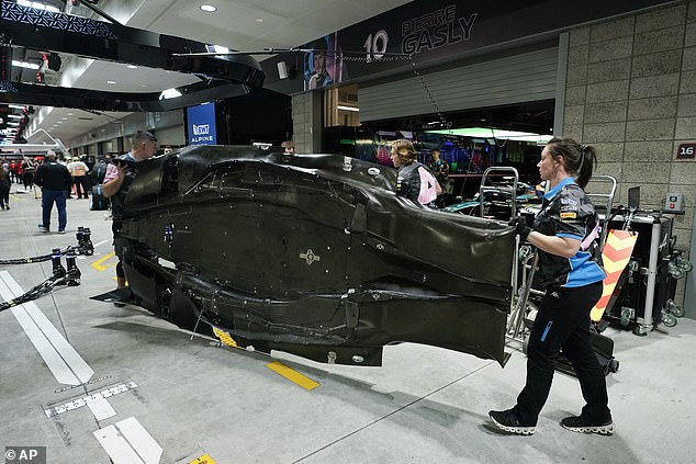 The Alpine crew checks Esteban Ocon's car for possible damage caused by the cover