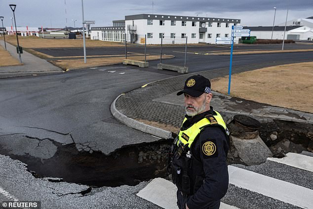 A police officer stands near the crack in a road in the fishing village of Grindavik, which was evacuated on November 15 due to volcanic activity in Iceland