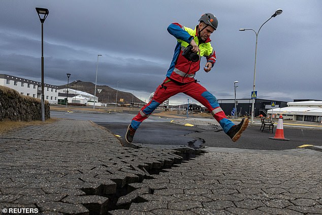 A search and rescue team member jumps over the crack in a road in the fishing village of Grindavik, which was evacuated due to volcanic activity, in Iceland on November 15