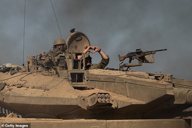 An IDF soldier makes a heart with his hands while sitting in a tank on November 17, 2023