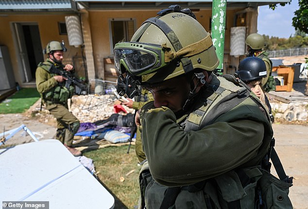 A soldier is overcome with emotion as he searches for bodies in the kibbutz