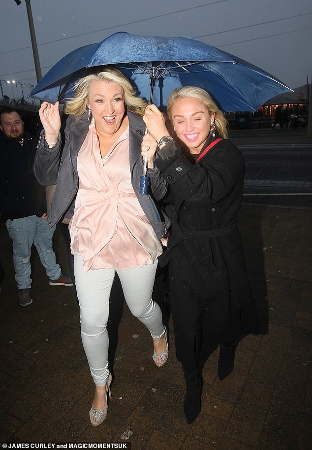 Windy: Former Strictly contestant Sara Davis (left) and snowboarder Aimee Fuller (right) sheltered from the rain as they arrived