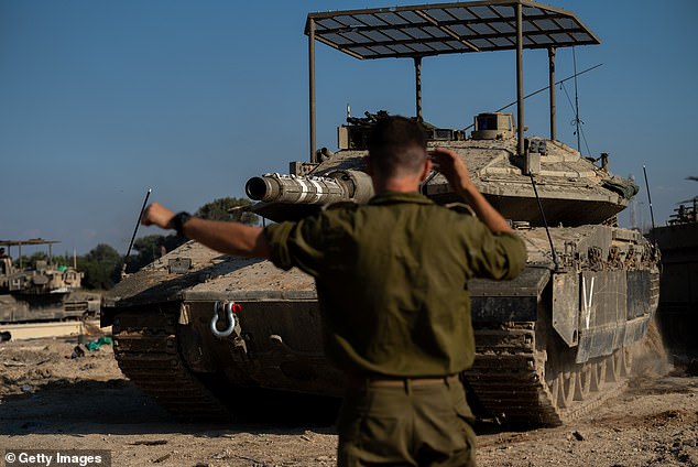 An IDF soldier directs a tank driver by gesturing near the northern border with Gaza on November 17, 2023