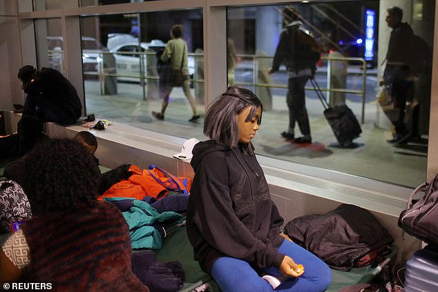 People slept on the floor and on couches with blankets over their heads in the airport terminal