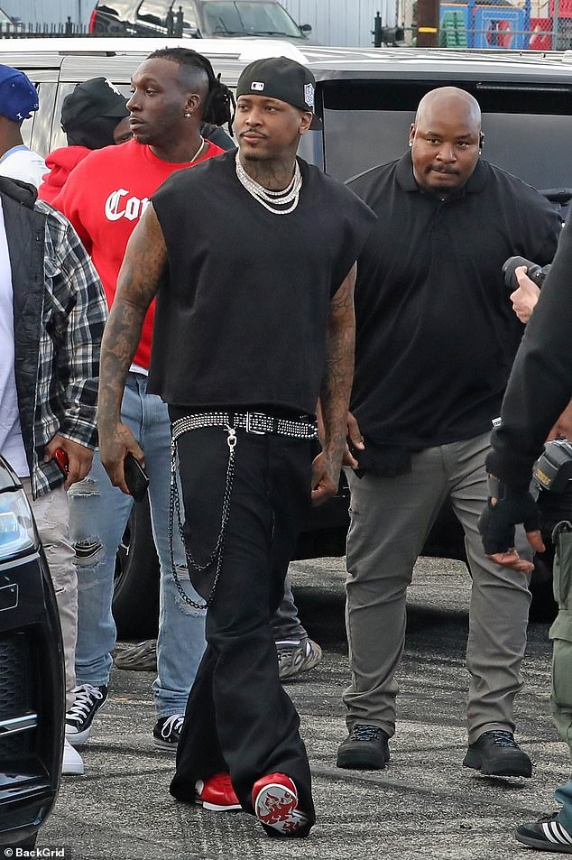 Stylish casual: A black cap was placed backwards on his head and the rapper added an assortment of sparkling, silver chains to complete the look