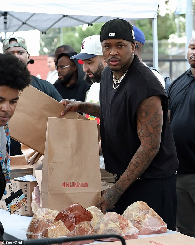 A helping hand: He was later seen standing at a table with cuts of meat and helping to fill large paper bags with food