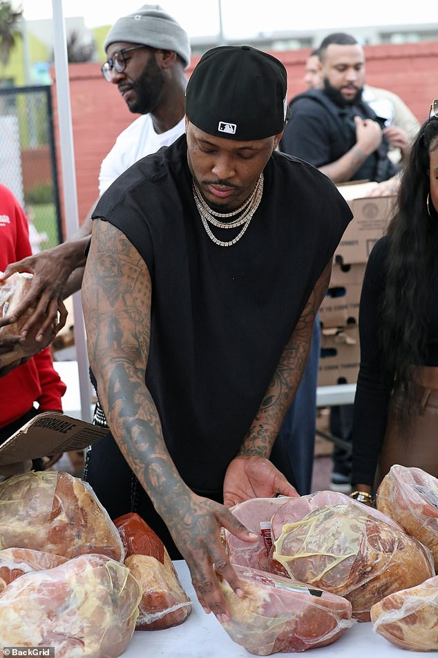 Preparation: YG was spotted at a table covered in what appeared to be ham that would be placed in a large paper bag to be given to families in need