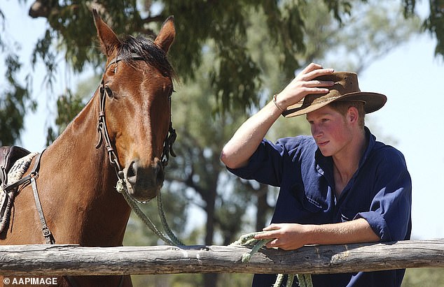 Prince Harry is pictured adjusting his Akubra hat while at a cattle station in South Queensland on November 27, 2003