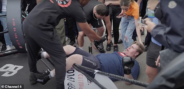 A heavyweight fighter falls to the ground outside the ring during a fight at the King of the Ring fight club in Manchester before being helped by the referee before continuing