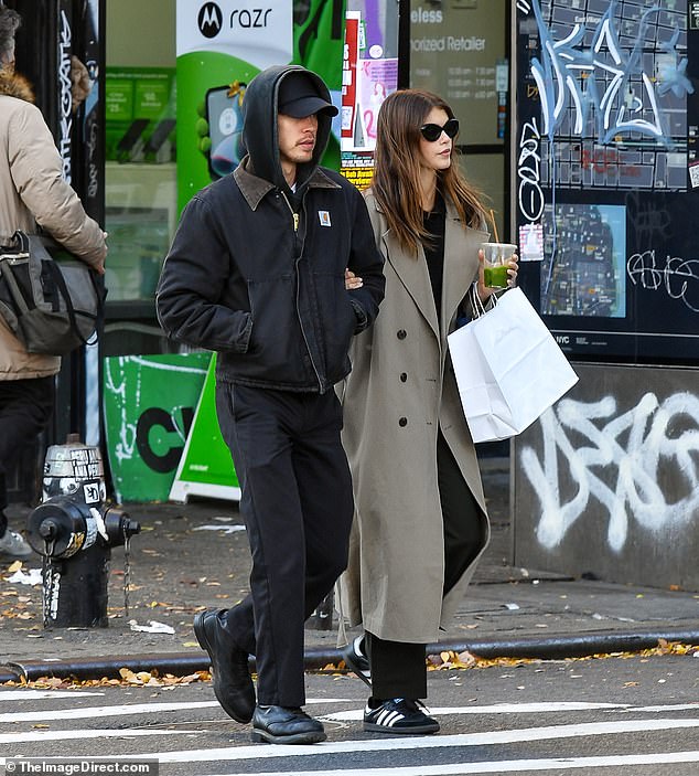 Fashion: Kaia, 22, wore black pants and a black top with a long, tan coat over it.  The runway veteran wore a black and white Adidas and added a pair of black cat-eye sunglasses to her face