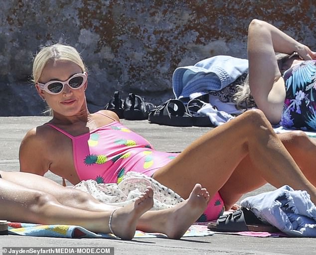 She had a large, white woven tote on hand, ready to carry all her beach essentials, including the bright pink towel she placed under her head.