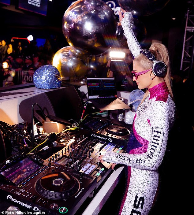 Custom costume: The DJ, 42, was dressed in a custom Formula 1 racing outfit featuring sequins in purple, pink and white with 'Hilton for the Stay' written across the front.  She wore dark sunglasses and styled her long, blonde hair in a high ponytail