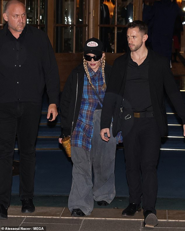 Need to stay hydrated: Madonna completed her look with chunky black sneakers and held a gold cup in her hand, her hair styled in the signature two braids