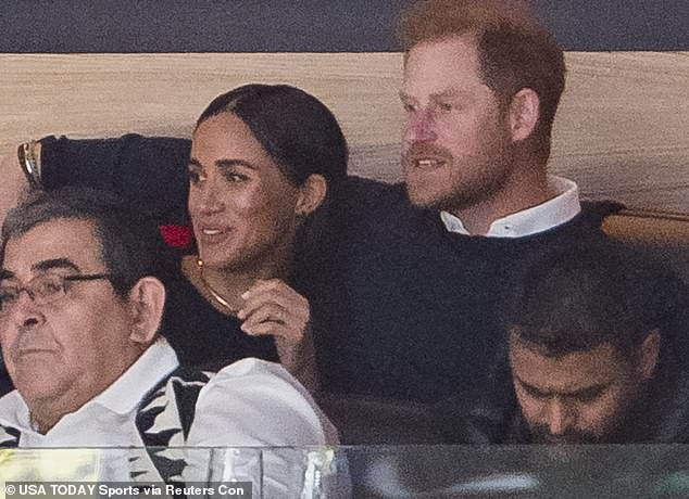 The Duke and Duchess of Sussex (pictured) are seen cozying up in their box at Rogers Arena last night