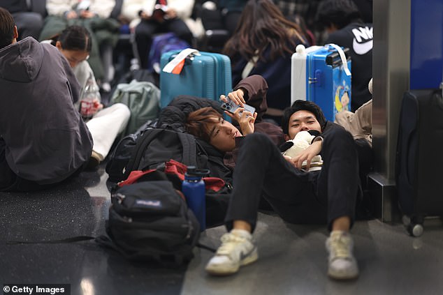 Travel chaos is already in full swing as storms hit the Plains and Midwest, delaying thousands of flights (Photo: Travelers wait for their flights at Chicago's O'Hare Airport)