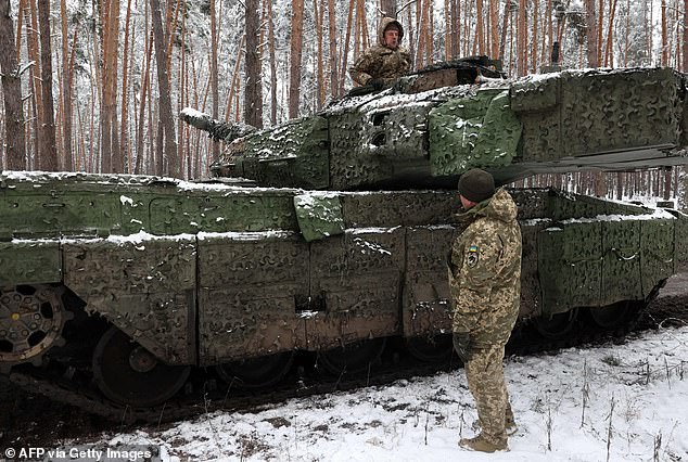 Ukrainian tank crew members of the 21st Mechanized Brigade talk on Tuesday while someone stands in the hatch of a German main battle tank Leopard 2A5 near the front line at an undisclosed location in the Lyman direction of the Donetsk region