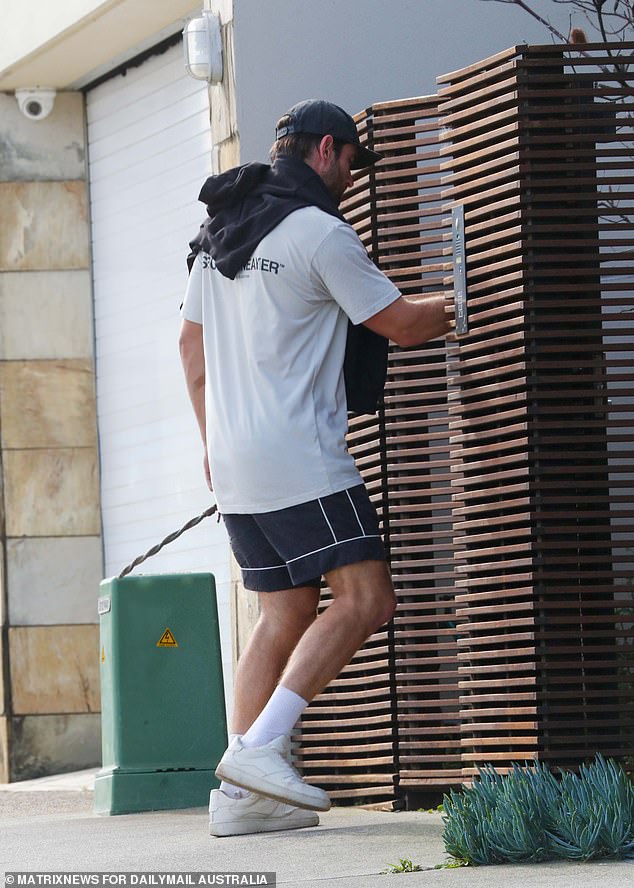 The athletic-looking man showed off his muscular body in a pair of short shorts, along with a T-shirt and sweater over his shoulders