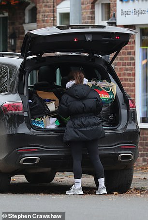 Busy: She was seen rummaging through the boot of her car, which was parked outside the repair shop, before going inside