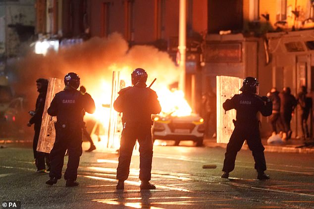 About 100 masked thugs fought battles with riot police (pictured last night), looted shops and set fire to a double-decker bus in anger over the attack, which also injured two adults - including a woman and the suspected knifeman