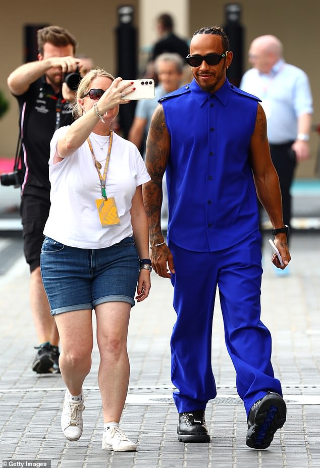 Star-struck: Lewis was pictured strolling along the Yas Marina Circuit track as a fan desperately tried to take a selfie with him