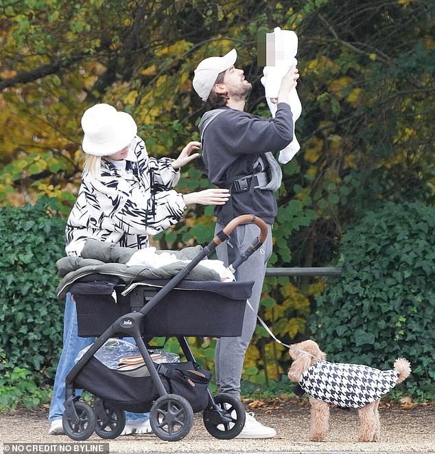 Doting parents: The couple watched Elsie as Roxy adjusted the papoose straps while Jack carried their daughter