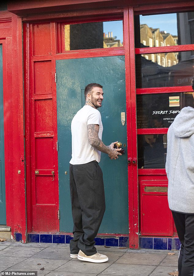 Snack time: The former footballer, 48, couldn't resist stopping by the Secret Sandwich Shop next door and stocking up on a few treats to take home to their Holland Park abode