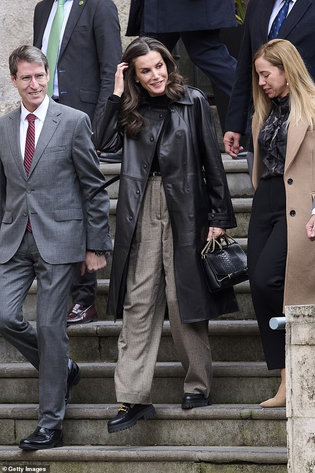 Letizia wore a beautiful leather knee-length coat with collar, which she paired with a simple black sweater and brown checked pants