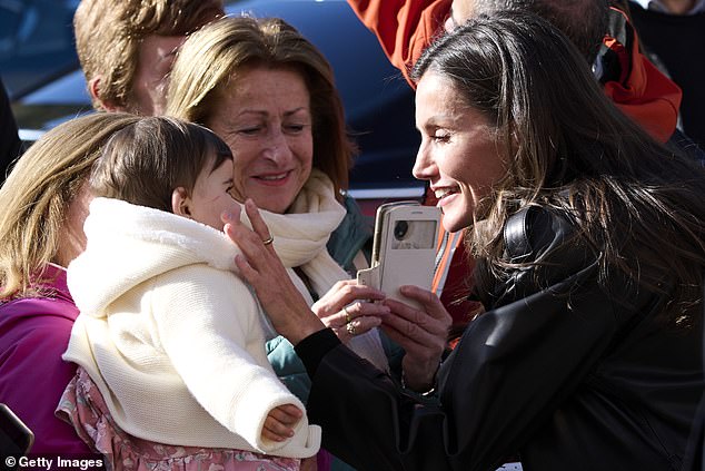 Letizia smiled as she met a baby while out for the meeting.  The baby's relative took a photo of her while she was handling the baby