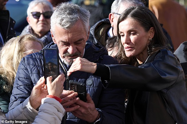 Letizia shields a man's phone from the sun while someone else takes a photo of the two of them