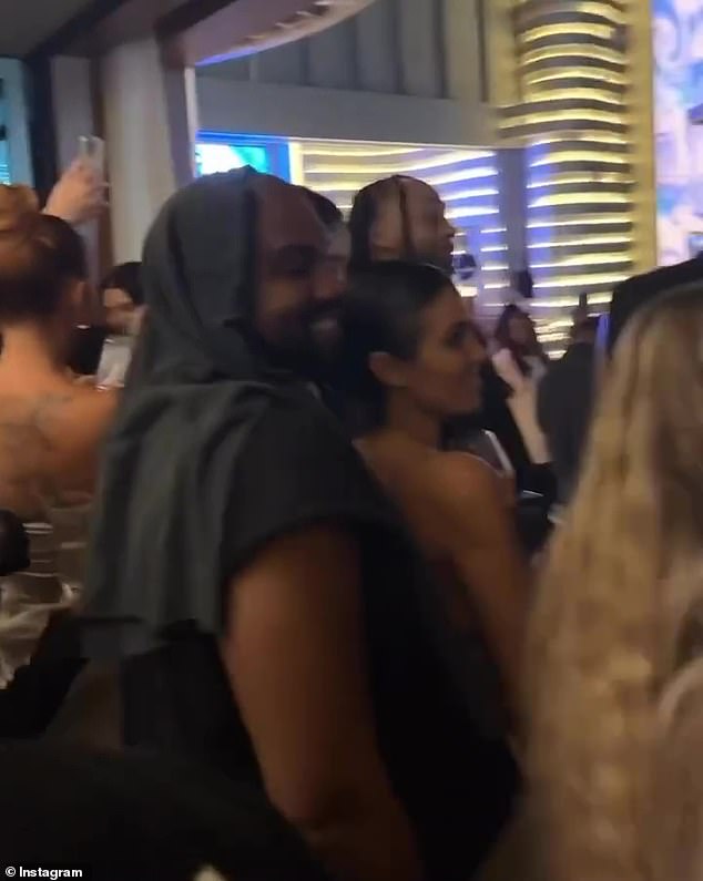 Intimate: The rapper got close to his wife as they watched the dancers show off.  He was dressed all in black and had a scarf or spare shirt draped over his head