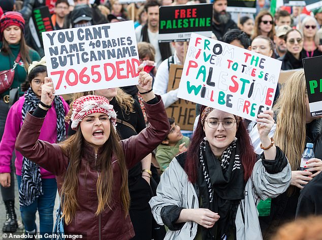 British lawyers for Israel say the chant 'From the river to the sea, Palestine will be free' is a 'well-known call for the destruction of the Jewish state of Israel'.  Pictured: A protester (right) holds a sign with the slogan during a march in London last month
