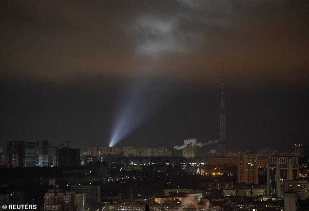 Ukrainian soldiers use a searchlight as they search the skies above the city for drones during a Russian drone strike