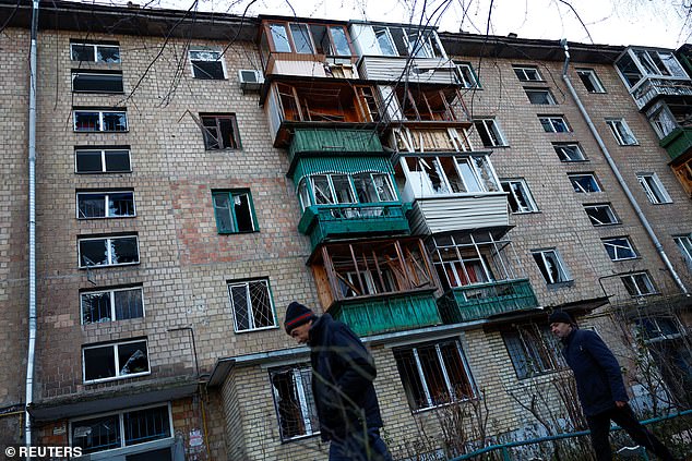 Local residents walk in front of their apartment building that has been damaged by Russian drone attacks