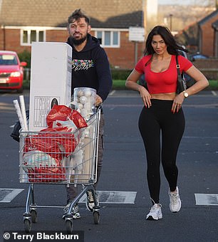 Taking turns: Johnny was also seen pushing the trolley as they stepped out to the parking lot