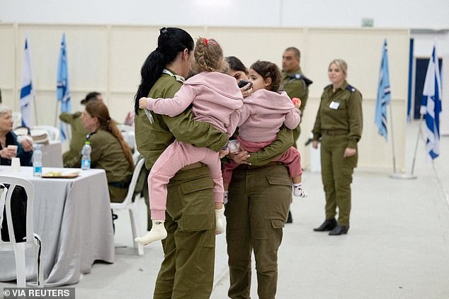Released Israeli child hostages are held by Israeli soldiers shortly after their arrival in Israel on November 24
