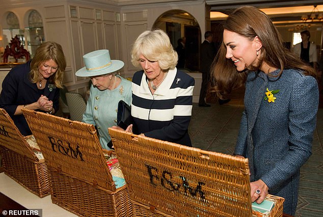 Queen Elizabeth, Camilla, Duchess of Cornwall and Catherine, Duchess of Cambridge (L-R) look at their baskets after receiving gifts at Fortnum and Mason food store in London, March 1, 2012